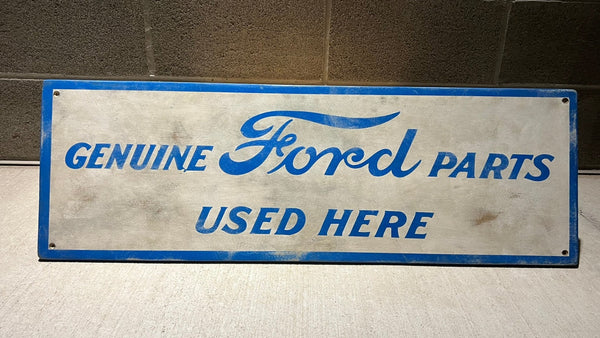 Vintage-style sign with 'Genuine Ford Parts Used Here' text on a white background with blue lettering.