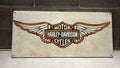Harley-Davidson logo on a wood sign against a brick wall.